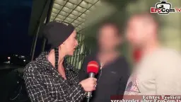 Milf mit Beanie und Blazer hält ein rotes Mikrofon und interviewt einen Mann nachts auf der Straße