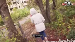 Junge Blondine in heller Jacke und Jeans läuft von hinten durch herbstlichen Parkweg zwischen Bäumen