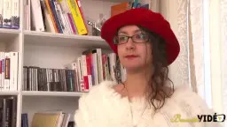 Milf mit rotem Hut und weißem Pelz lächelt lasziv in die Kamera, während ein Männerarm ihre Hand hält.