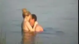 Blondes Mädchen umarmt nackten Mann leidenschaftlich im Wasser