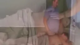 Reife Oma im bunten Rock sitzt auf dem Bett, während der junge Mann im blauen Shirt vor ihr steht.