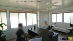 Blonde Anni Angel in engen Jeansshorts und grünem Top steht lasziv am Fenster und zeigt ihren flachen Bauch.