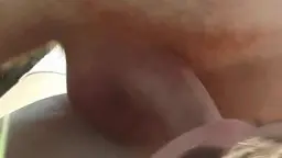 Vollbusige Deutsche kniet oben ohne auf einer Picknickdecke und wichst einen liegenden Mann im Gras.