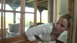 Blonde Milf im weißen Shirt telefoniert auf der Terrasse mit Einkaufstasche in der Hand