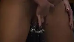 Nackte Frau mit verbundenen Augen wird von starken Händen auf dem Boden liegend tief in den Mund gefickt.