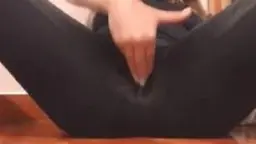 Nahaufnahme einer Frau in schwarzer Leggings, die mit zwei Fingern ihre nasse Spalte durch den Stoff reibt.